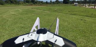 drone acoplado em um pequeno trilho de lançamento inclinado e apoiado no chão de grama