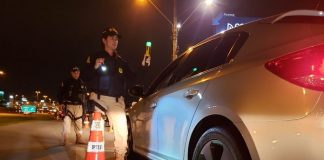 policial feminina com bafômetro passivo ao lado de chevrolet cruze em blitz