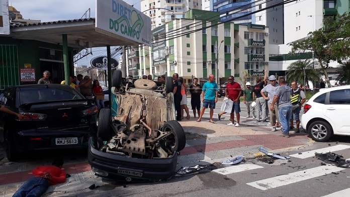 carro capotado ao lado de fruteira em uma esquina