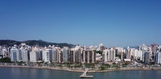 baía da beira-mar norte em foto aérea mostrando barco na água, trapiche, avenida e linha de prédios