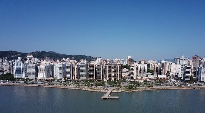 baía da beira-mar norte em foto aérea mostrando barco na água, trapiche, avenida e linha de prédios