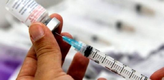 pessoa retira com seringa dose de vacina de uma ampola