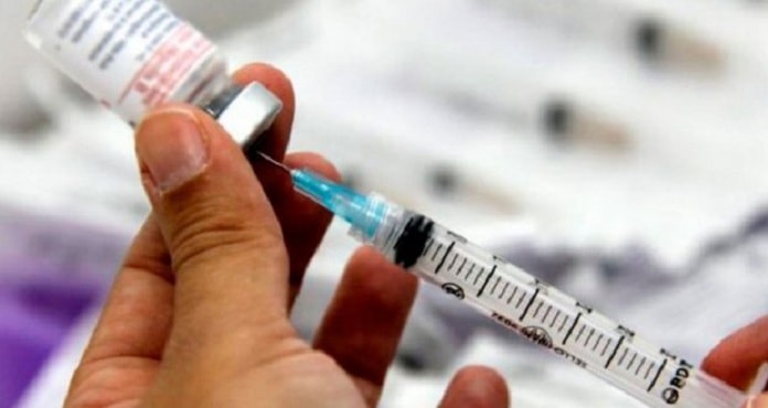 pessoa retira com seringa dose de vacina de uma ampola