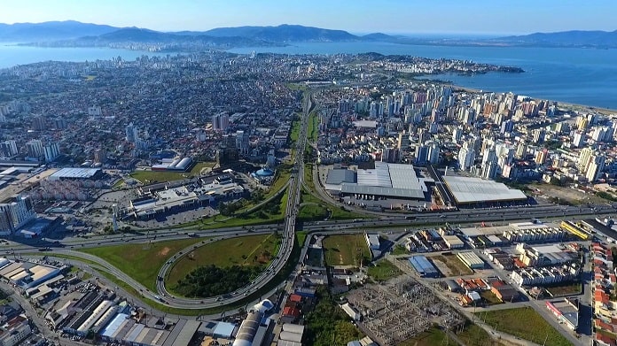 foto aérea da grande florianópolis mostrando as duas cidades, ilha ao fundo