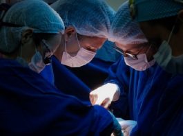 três cirurgiões fazendo um procedimento cirúrgico