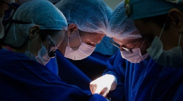 três cirurgiões fazendo um procedimento cirúrgico