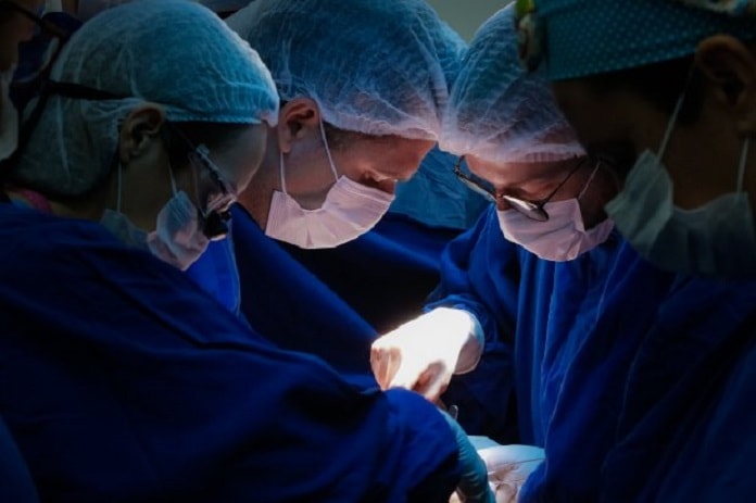três cirurgiões fazendo um procedimento cirúrgico