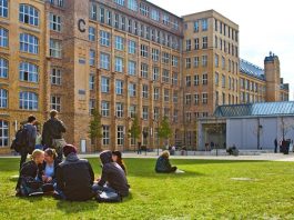 Udesc oferece 19 bolsas de intercâmbio para segundo semestre jovens sentados em roda em gramado de uma universidade do exterior, com grande edifício histórico ao fundo