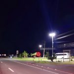 trecho da rodovia com ciclofaixa em foto noturna com alguns imóveis na beira da rodovia