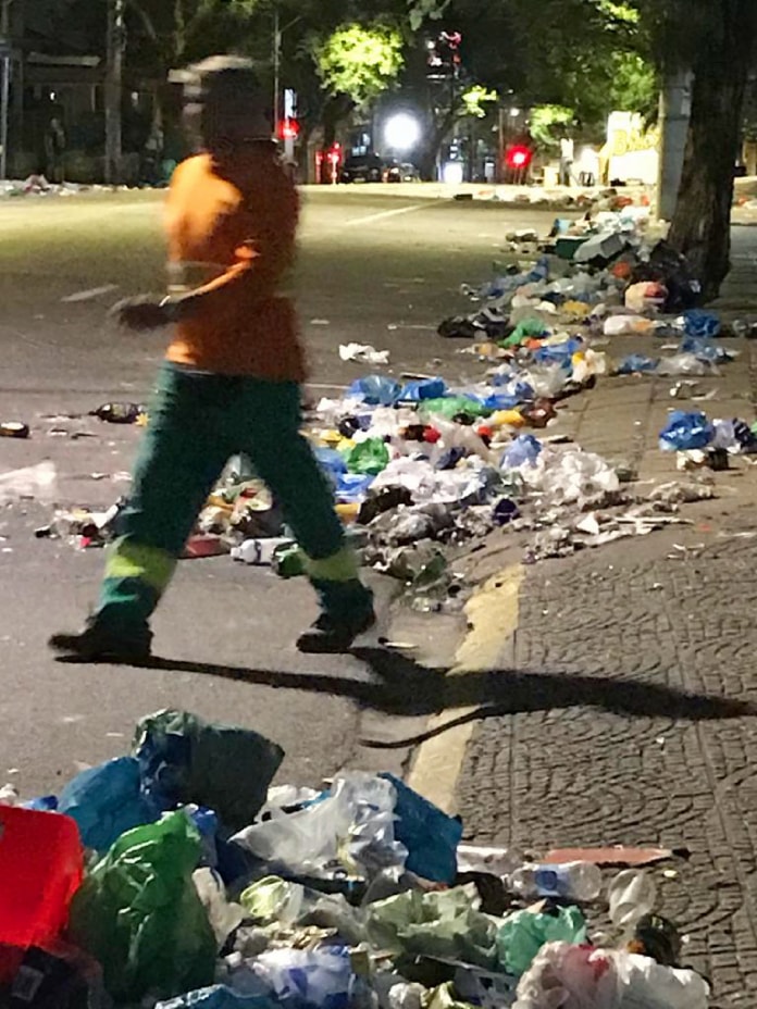 trabalhador uniformizado da comcap passa por meio-fio cheio de lixo após o carnaval