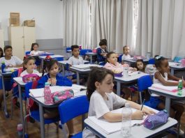 26 mil alunos voltam às aulas na rede municipal de São José na segunda (17) crianças uniformizadas sentadas em carteiras de sala de aula