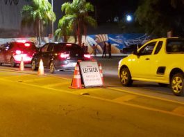carros passando por uma blitz com placa "lei seca"