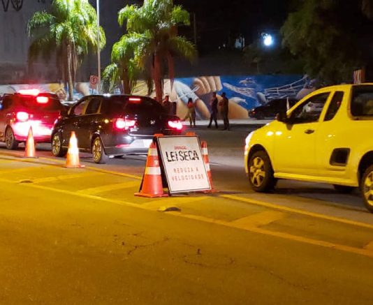 carros passando por uma blitz com placa "lei seca"