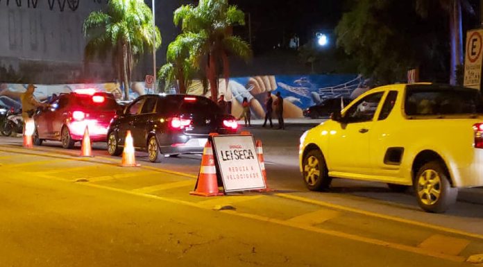 carros passando por uma blitz com placa "lei seca"