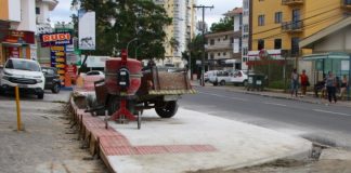 obra da calçada, com altura maior que as vagas de comércio, betoneira sobre a calçada e comércios em volta