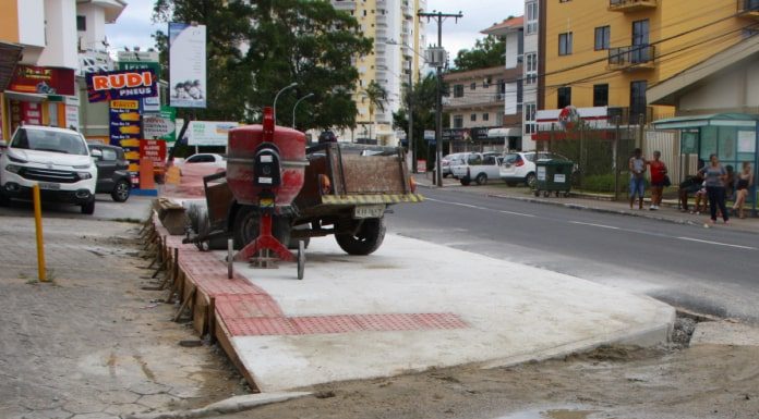 obra da calçada, com altura maior que as vagas de comércio, betoneira sobre a calçada e comércios em volta