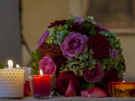 duas velas acesas ao lado de um buquê de casamento