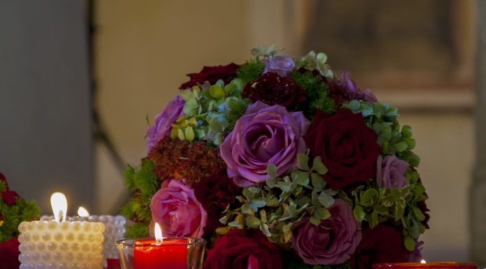 duas velas acesas ao lado de um buquê de casamento