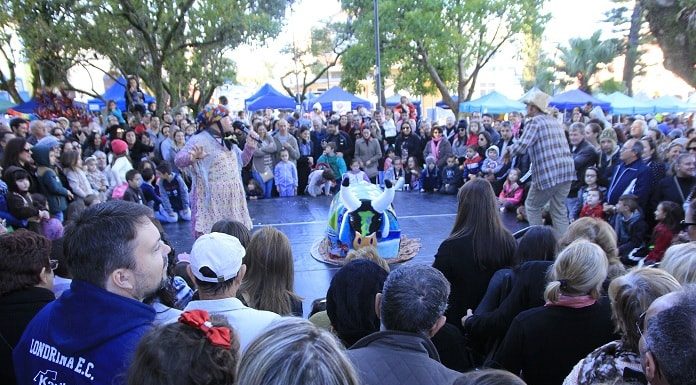 grande grupo de pessoa em volta de um palco baixo onde há apresentação do boi de mamão