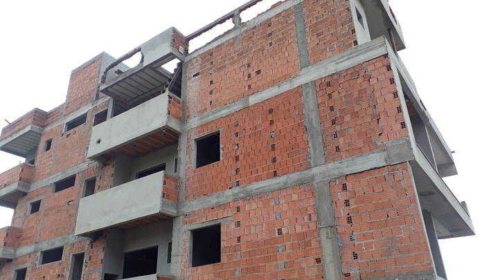 fachada do prédio em construção com vigas de concreto e paredes de tijolos à mostra