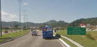 ônibus e carro passando pela via expressa sul e placa ao lado "rodovia aderbal ramos da silva"