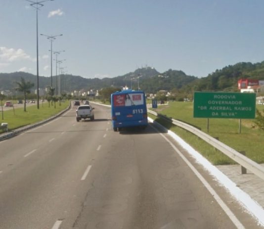 ônibus e carro passando pela via expressa sul e placa ao lado "rodovia aderbal ramos da silva"