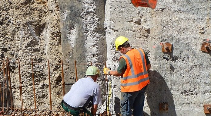 Empregos em Santa Catarina: dois operários com equipamentos de proteção sobre estrutura de ferro dentro de grande buraco de obra