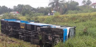 ônibus tombado de lado no meio de um terreno