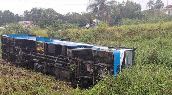 ônibus tombado de lado no meio de um terreno