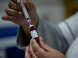 Inicia na segunda-feira vacinação ao sarampo e reforço contra febre amarela pessoa retira dose de vacina da ampola com uma agulha em seringa