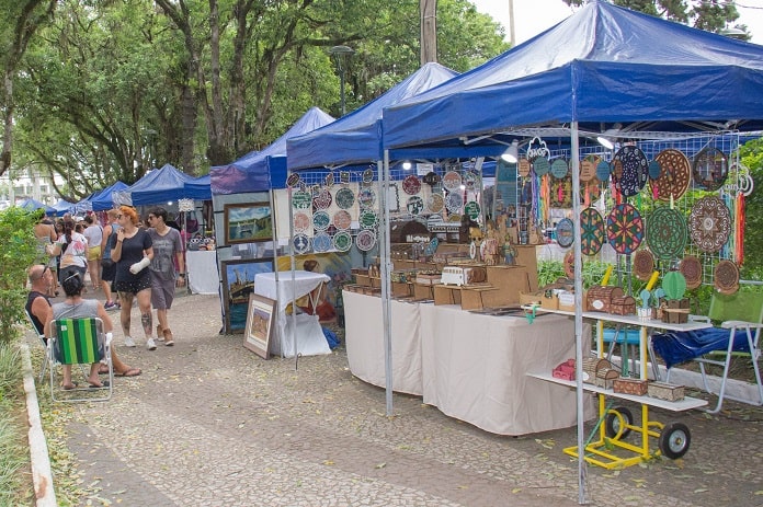 barracas de feira na praça e pessoas andando