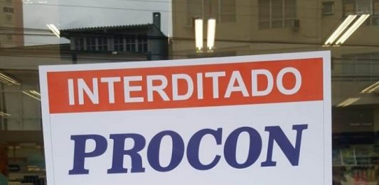 Farmácia é interditada por aumentar o preço do álcool em gel de forma abusiva placa afixada no vidro escrita interditado procon com data