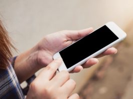 moça olha para a tela do celular em sua mão