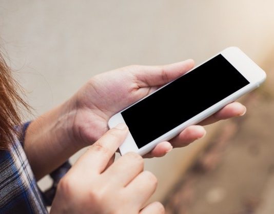 moça olha para a tela do celular em sua mão