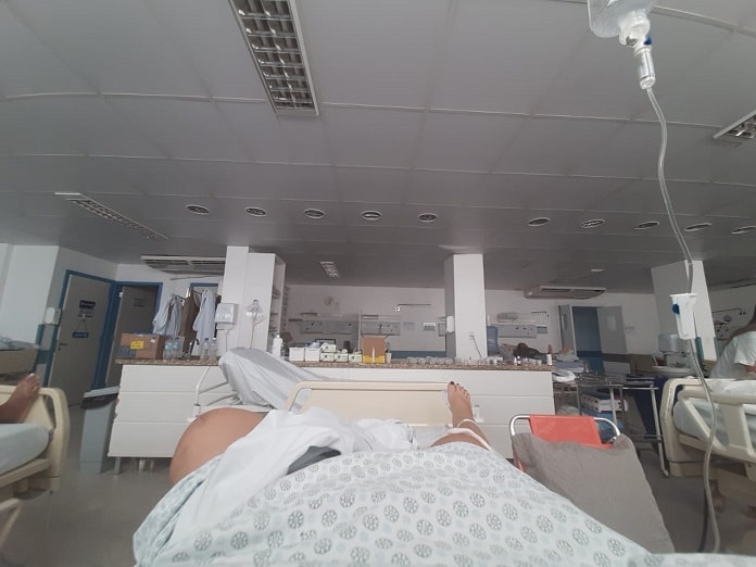 mulher deitada em cama de hospital com os pés para frente em enfermaria vazia