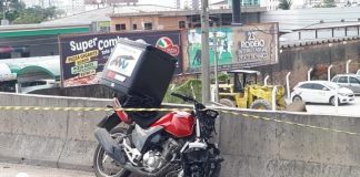 moto com baú batida e amassada apoiada na mureta de concreto da br 101 com uma fita zebrada por cima