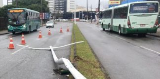 poste caído no canteiro central da avenida com cones delimitando e ônibus da jotur ao fundo e outro do outro lado