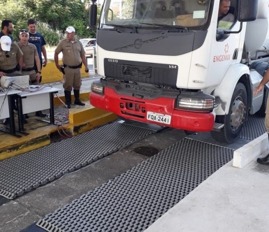 Rodovias estaduais terão balanças móveis para aferir peso de caminhões caminhão estacionando sobre a balança com policias em volta