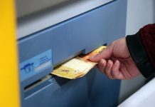 Mão de um homem sacando notas de R$ 20,00 em um caixa eletrônico