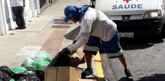 Comcap começa retomada da coleta seletiva gari da comcap se baixa para pegar caixas e sacolas de lixo em calçada