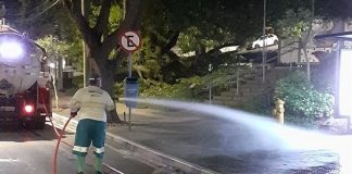 funcionário da comcap lava calçada em frente ao hemosc de noite com grande jato de água