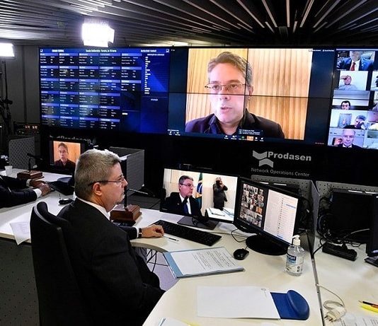 “Coronavaucher”: Senado aprova auxílio emergencial de R$ 600 para autônomos vice-presidente do senado sentado em mesa com dois monitores e na parede diversos outros monitores