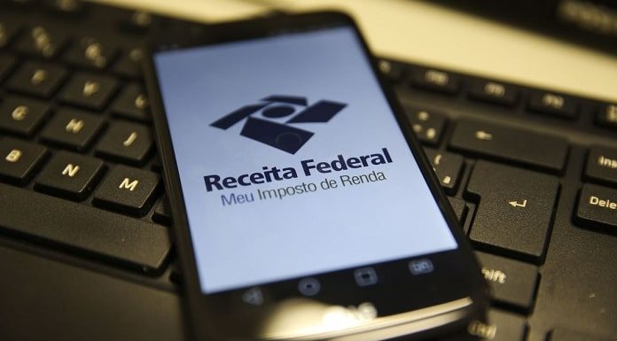 celular com logo da receita federal ocupando toda tela sobre teclado de computador