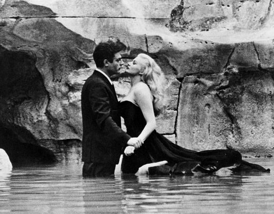cena do filme em que homem e mulher abraçados na água do mar próximo ao costão