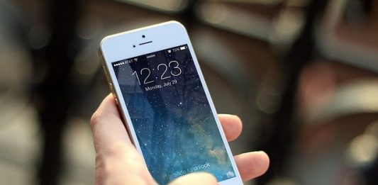 close em pessoa segurando um iphone com tela ligada