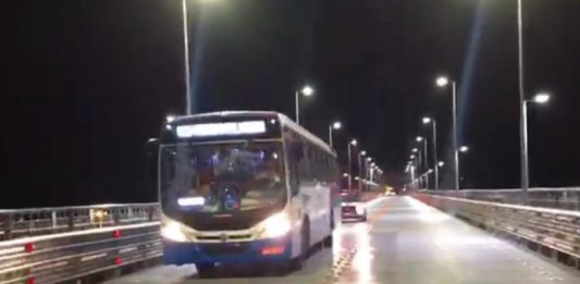 ônibus do transporte coletivo municipal saindo da ponte hercílio luz à noite com viatura atrás