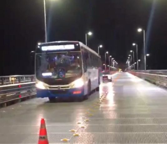 ônibus do transporte coletivo municipal saindo da ponte hercílio luz à noite com viatura atrás
