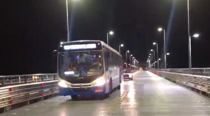 ônibus do transporte coletivo municipal saindo da ponte hercílio luz à noite com viatura atrás