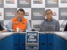 quatro pessoas em bancada com painel do governo ao fundo