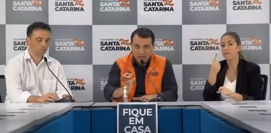 “Não há ninguém para o nosso governo que seja descartável”, diz Moisés moisés em bancada com secretário de saúde ao lado e do outro intérprete de libras